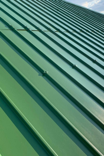 malowanie-dachu-blaszanego-farba-royal-na-goraco-grupa-biotop-krakow Fragment eines grün gestrichenen Blechdachs